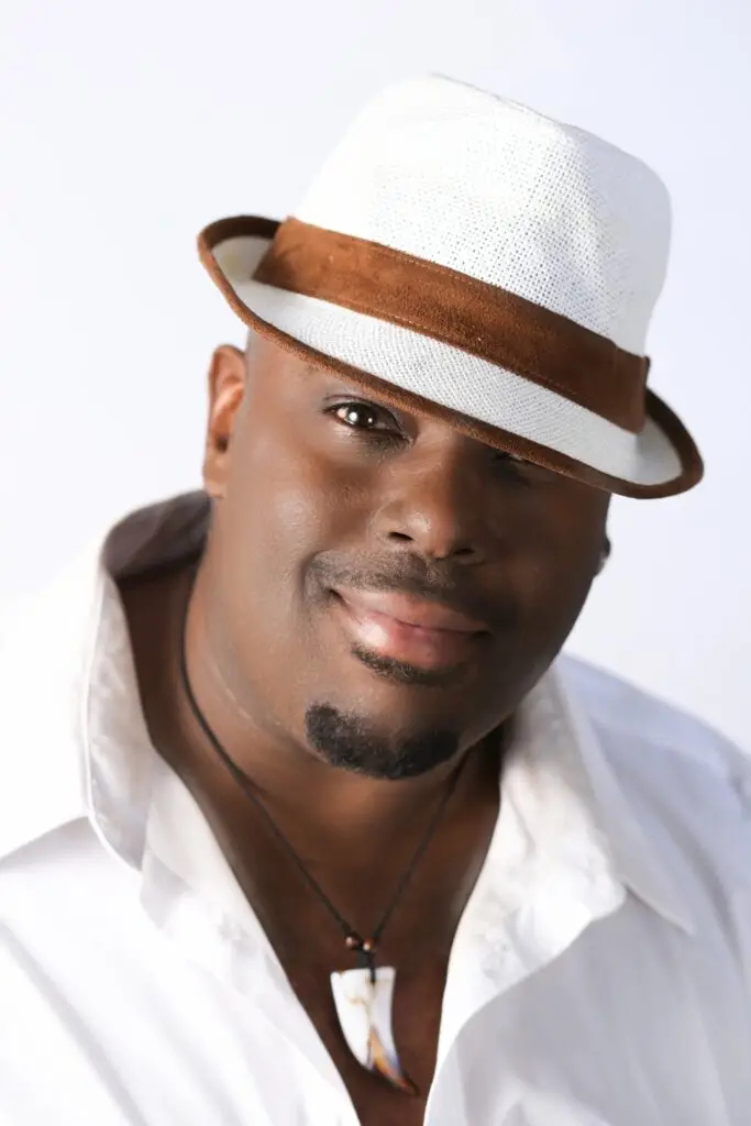 Ray, smiling, wearing a white shirt and a white hat.